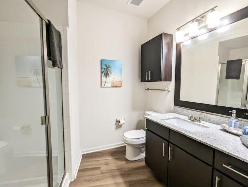 a bathroom with a sink and a toilet and a mirror at League Flats South End at South Blvd in Charlotte