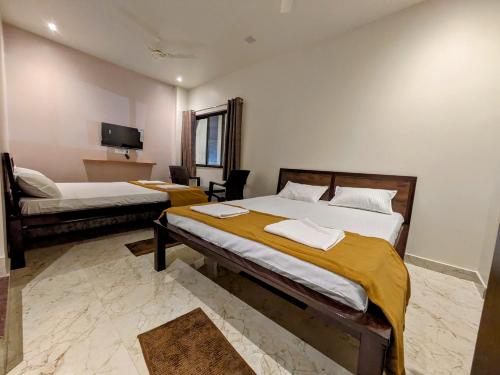 Habitación de hotel con 2 camas y TV en Hotel Madhusudan Executive, en Kolhapur