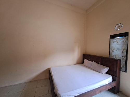 a small bedroom with a bed with white sheets at SPOT ON 93465 Archa Guest House Syariah in Jambi
