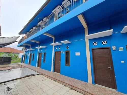 a blue building with brown doors on it at SPOT ON 93465 Archa Guest House Syariah in Jambi