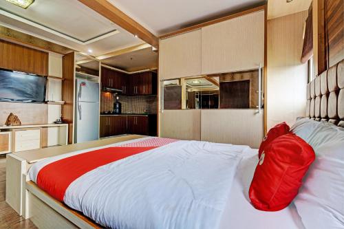 een slaapkamer met een groot bed en een rode deken bij OYO 93426 Metro Suites Apartment By Goodvibes in Bandung