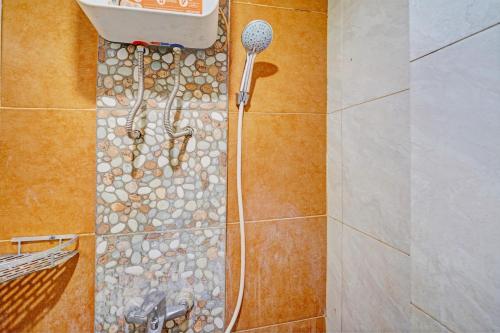 een badkamer met een douche en een stenen vloer bij OYO 93426 Metro Suites Apartment By Goodvibes in Bandung