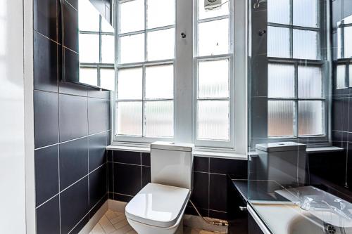 a bathroom with a toilet and a sink and windows at Contemporary Open Plan Penthouse in London