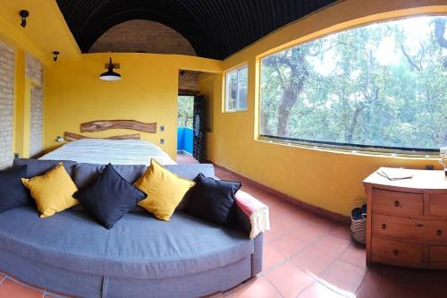 a bedroom with a bed and a large window at La Cabaña Negra al fondo del Bosque de Tepoztlán in Tepoztlán