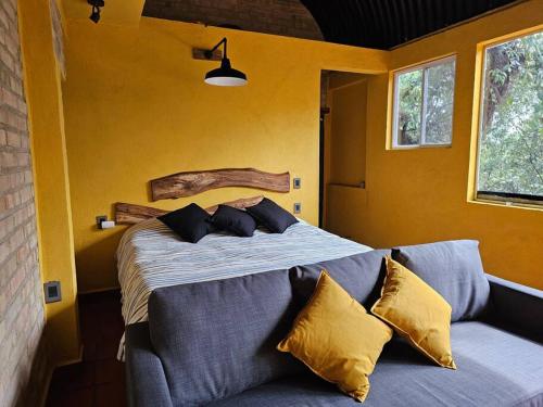 a bedroom with a large bed with yellow walls at La Cabaña Negra al fondo del Bosque de Tepoztlán in Tepoztlán