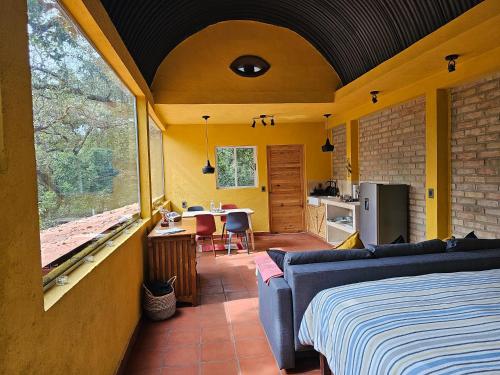 a bedroom with a bed and a kitchen with a table at La Cabaña Negra al fondo del Bosque de Tepoztlán in Tepoztlán