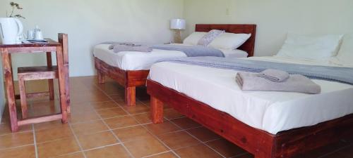 a room with three beds and a table with a mirror at Toafa Lodge in ‘Ohonua