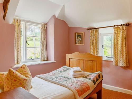 a small bedroom with a bed and two windows at 3 Bed in Beaminster 50738 in Stoke Abbott