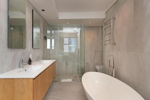 ein Badezimmer mit zwei Waschbecken, einer Badewanne und einer Dusche in der Unterkunft The Cosmo Luxury Suites by Totalstay in Kapstadt
