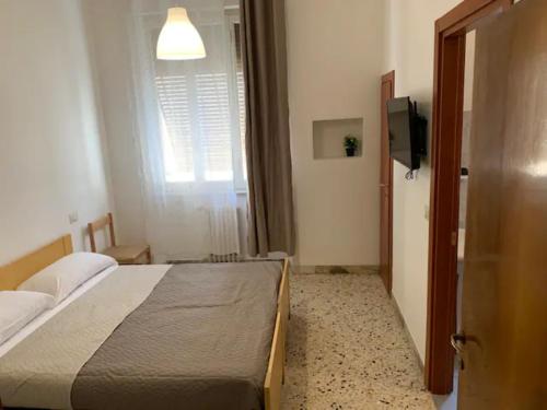1 dormitorio con 1 cama, TV y ventana en Daniele rooms en Arezzo