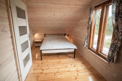 małą sypialnię z łóżkiem w małym domku w obiekcie Mazury w Pigułce- domek z sauną i balią, Woszczele w mieście Ełk