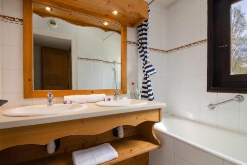 La salle de bains est pourvue de 2 lavabos, d'un miroir et d'une baignoire. dans l'établissement Appartement Anaïte 15 - Happy Rentals, aux Houches