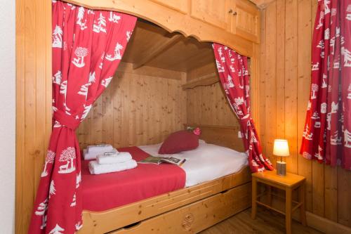 レ・ズッシュにあるAppartement Anaïte 15 - Happy Rentalsの赤いカーテンが付いた木製の部屋の小さなベッド1台