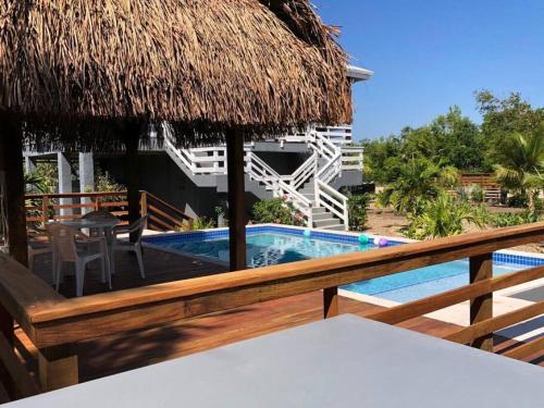 un complejo con piscina y sombrilla de paja en La Vida Belize - Casa, en Riversdale