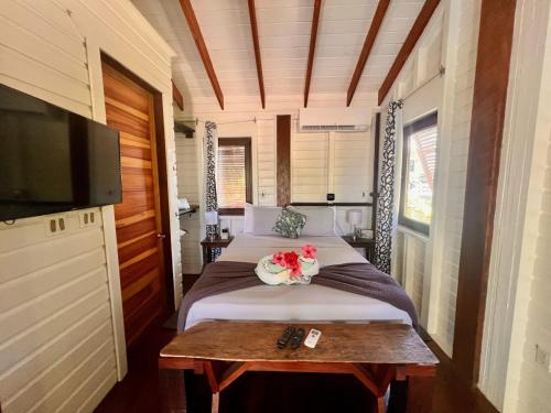 a bedroom with a bed and a table with flowers on it at La Vida Belize - Casita in Riversdale