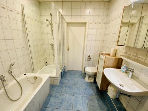 bagno con vasca, lavandino e servizi igienici di Promenadenblick/Captains-Suite a Warnemünde