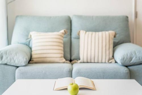 a blue couch with a book and a apple on a table at 4Brothers in Cala'n Porter