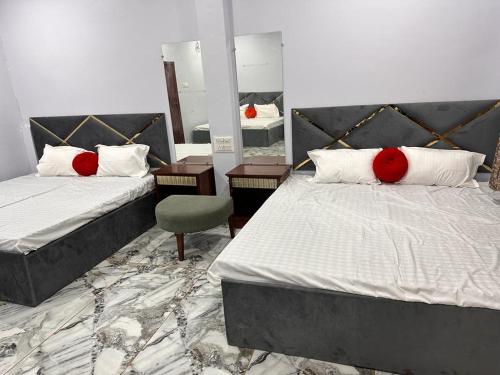 a bedroom with two beds with red pillows and a mirror at Garden Villa hotel in Ujjain