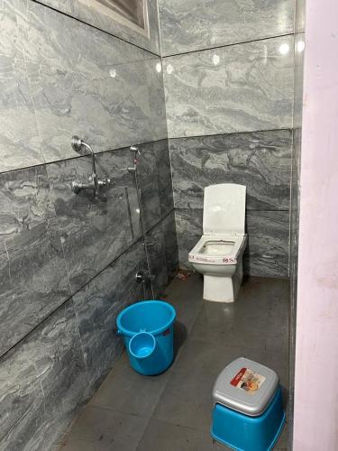 a bathroom with a toilet and a blue bucket at Garden Villa hotel in Ujjain