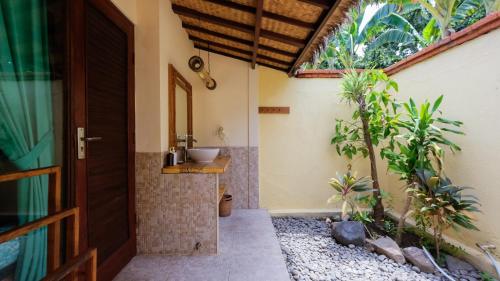 a bathroom with a sink next to a door at Taman Sari Bali Resort and Spa in Pemuteran