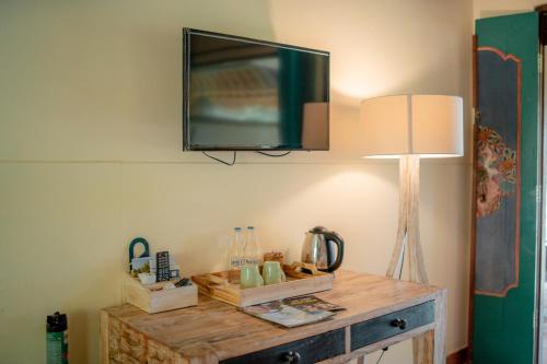 a tv hanging on a wall with a wooden table at Taman Sari Bali Resort and Spa in Pemuteran