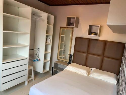 um quarto com uma cama, prateleiras e um espelho em Studio Residencial Curitiba Apartament em Curitiba