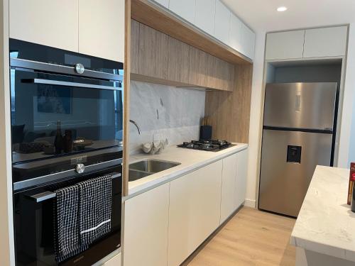 a kitchen with a sink and a refrigerator at Serenity Stayz - 3 Bedroom Apartment in Melbourne CBD in Melbourne