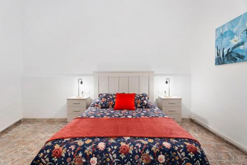 a bedroom with a large bed with a red pillow at La Casa de Tina in Playa de San Juan