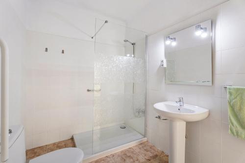 baño blanco con ducha y lavamanos en La Casa de Tina en Playa de San Juan