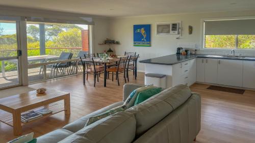 a living room with a couch and a kitchen and a table at Island View 1 in Coffin Bay