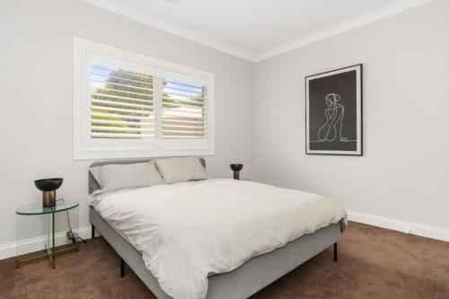 a white bedroom with a bed and a window at Top of town in Mount Martha