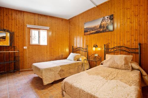 two beds in a room with wooden walls at Casa Doña Margarita in Tuineje