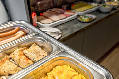 two metal trays of food on a kitchen counter at Cotton House in Łódź