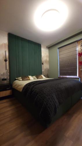 a bedroom with a large bed with a green headboard at Pinewood ANG premium luxurious apartment 15 in Borovets