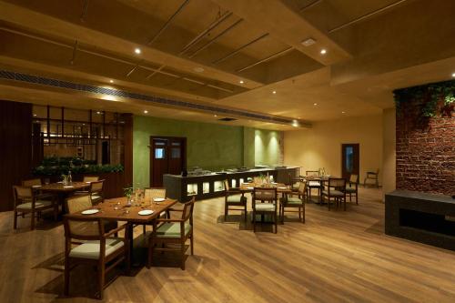 a restaurant with wooden tables and chairs and a fireplace at Ikshana Resort and Spa, Khandala in Lonavala