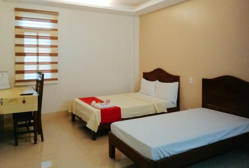 um quarto com 2 camas, uma secretária e uma mesa em RedDoorz @ Capitol View MC Inn Nueva Vizacaya em Bayombong
