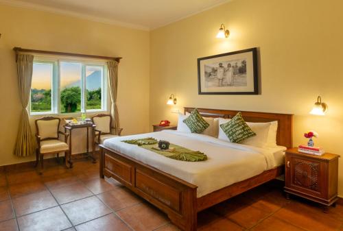 Schlafzimmer mit einem Bett, einem Tisch und einem Fenster in der Unterkunft Wild Pastures by Nature Stays in Masinagudi