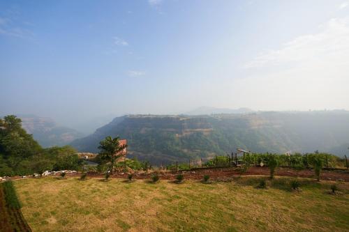 a field with a view of a mountain at Ikshana Resort and Spa, Khandala in Lonavala