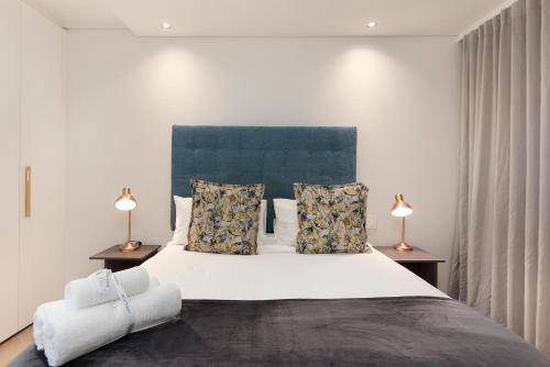ケープタウンにあるThe Cosmo Luxury Suites by Totalstayのベッドルーム(白い大型ベッド、ランプ2つ付)