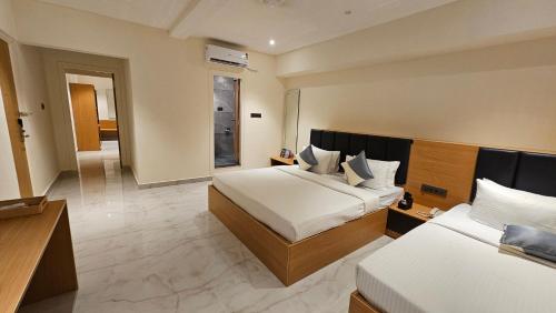 a hotel room with two beds and a bathroom at Emerald Urban Comforts in Mysore