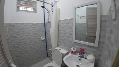 a bathroom with a toilet and a sink and a shower at Queenslander Hotel and Restaurant in Alaminos