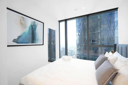 een slaapkamer met een wit bed en een groot raam bij Brand NEW Modern Luxury Lvl 37 Home in the Clouds in Melbourne