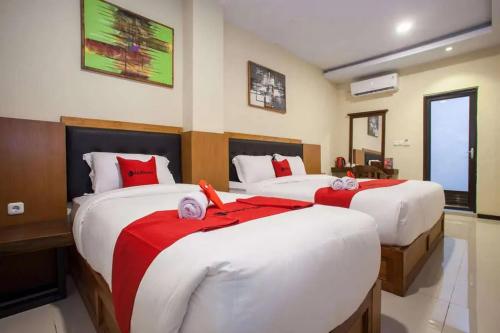 1 dormitorio con 2 camas con sábanas rojas y blancas en RedDoorz Premium @ Jalan Cengkeh Malang, en Malang