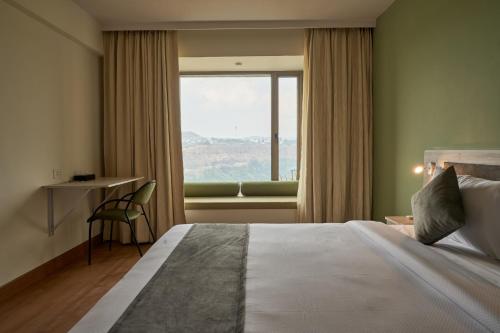 a hotel room with a bed and a window at Ikshana Resort and Spa, Khandala in Lonavala