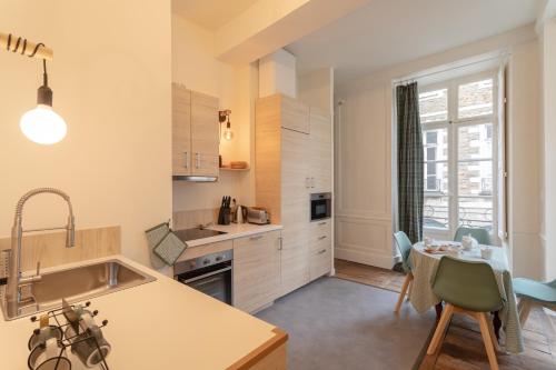 - une cuisine avec un évier et une table avec une salle à manger dans l'établissement La Blanche Hermine - Appartement centre de Rennes, à Rennes