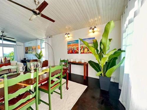 a dining room with green chairs and a table at KK Sunset Villa- Full Sunset Balcony, Mosquito Free, 4K TVs, 5G WIFI and more! in Kota Kinabalu