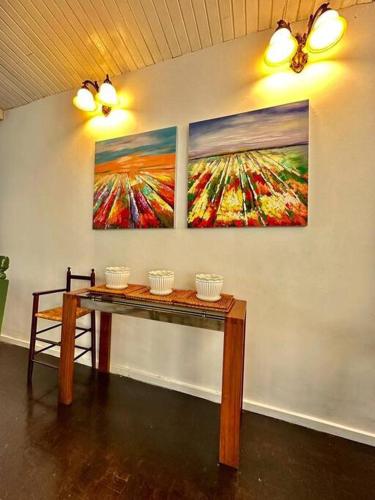 a table in a room with three paintings on the wall at KK Sunset Villa- Full Sunset Balcony, Mosquito Free, 4K TVs, 5G WIFI and more! in Kota Kinabalu