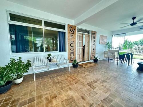 a living room with two white benches and plants at KK Sunset Villa- Full Sunset Balcony, Mosquito Free, 4K TVs, 5G WIFI and more! in Kota Kinabalu