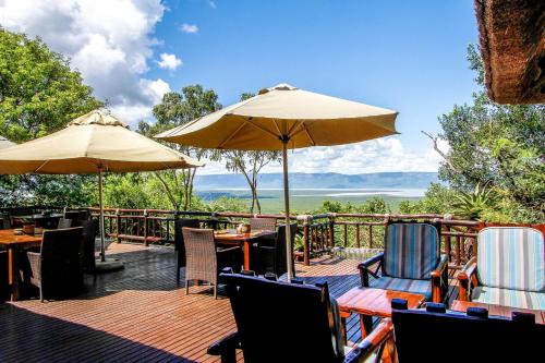 a deck with tables and chairs and umbrellas at Shayamoya Tiger Fishing and Game Lodge in Pongola Game Reserve