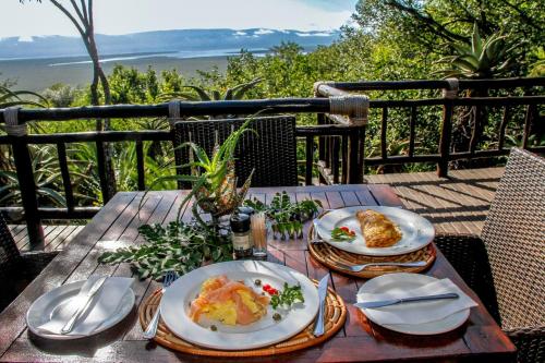 una mesa de madera con platos de comida. en Shayamoya Tiger Fishing and Game Lodge, en Pongola Game Reserve